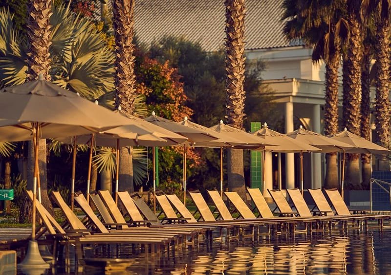 Espreguiçadeiras e guarda-sóis à beira da piscina do Jardins de Jurema ao entardecer